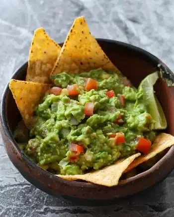 Bol de guacamole frais avec des légumes et des chips tortilla