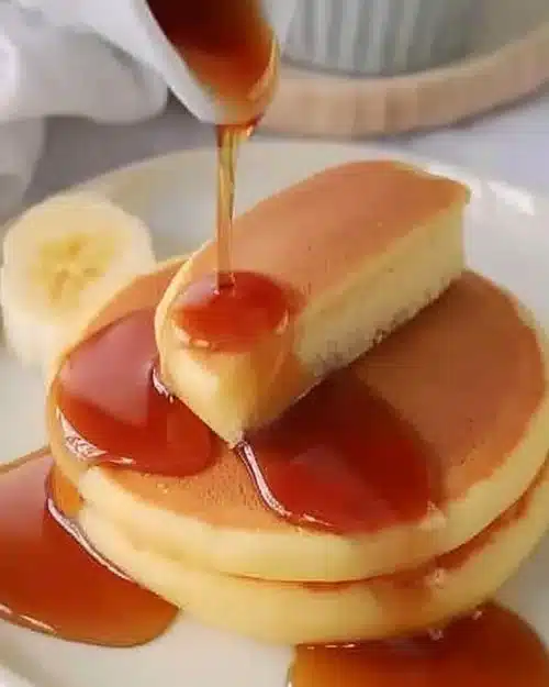 Pancakes fluffy japonais dorés et moelleux, servis avec du sirop d'érable.