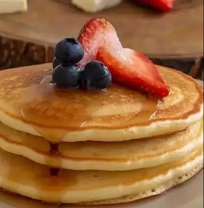 Pancakes moelleux et dorés servis avec du sirop d'érable et des fruits frais