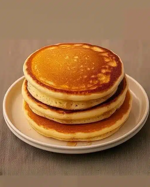 Pancakes moelleux en portion sur une assiette, garnis de sirop d'érable et fruits