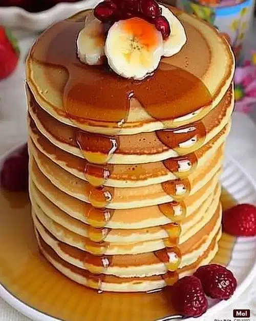 Pancakes moelleux sur une assiette avec des fruits frais et du sirop