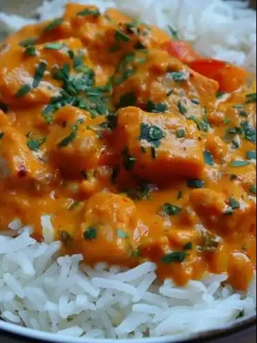 Creamy pumpkin curry dish garnished with herbs and spices.