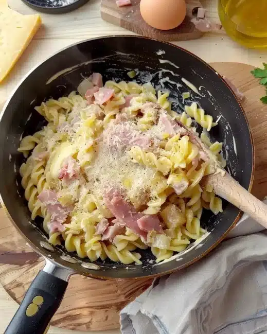 Delicious pasta with ham and melted raclette cheese served on a plate.
