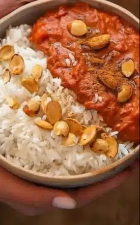 Bowl of Pumpkin Mafé with spices and herbs garnish