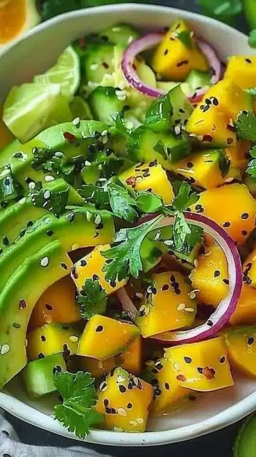 Salade de concombre, mangue et avocat garnie d'herbes fraîches
