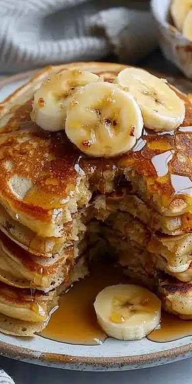 Pancakes à la banane garnis de tranches de banane et de sirop d'érable.